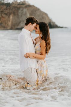 a man and woman are standing in the water at the beach with their arms around each other