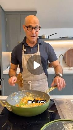 a man in an apron is cooking some food on the kitchen stove and he is holding a wooden spoon