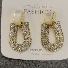 Elegant Clear Rhinestone Dangle Earrings Post Backs Medium Weight Gold Colored Setting Diamond White Crystal Earrings For Party, White Crystal Dangle Earrings With Diamond Accents, Chic Crystal Earrings With Rhinestones, Glamorous White Crystal Earrings With Diamond Accents, Glamorous White Crystal Earrings With Bling, Glamorous White Dangle Crystal Earrings, White Crystal Earrings With Bling, Diamond White Rhinestone Earrings, White Bling Crystal Earrings In Cubic Zirconia