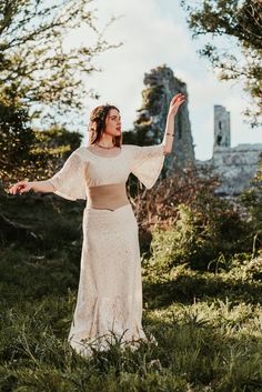 a woman standing in the grass with her arms outstretched