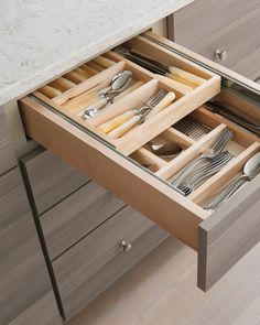 an open drawer with utensils and silverware in it on a countertop