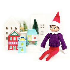 an elf doll sitting in front of some small houses