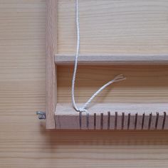 a piece of wood is tied up to a wooden shelf with white string hanging from it