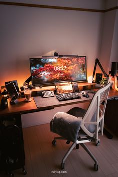 a computer desk with a laptop, keyboard and mouse on it in front of a monitor