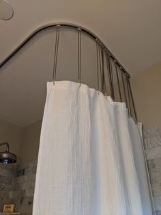 a white shower curtain hanging from the ceiling