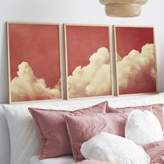 three paintings on the wall above a bed with pink pillows and white sheets in a bedroom