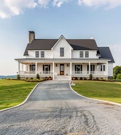 a large white house sitting on top of a lush green field next to a road