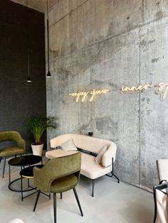 a room with chairs, couches and a neon sign on the wall