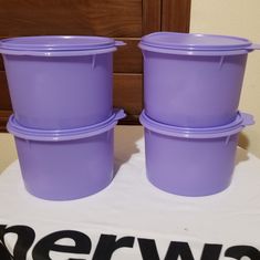 three purple plastic containers sitting on top of a white table next to a brown wall