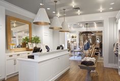 the inside of a clothing store with lots of clothes on display and lights hanging from the ceiling