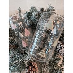 two wine glasses sitting next to each other on top of a christmas tree covered table