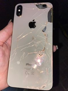 an iphone that has been cracked and is being held in someone's hand