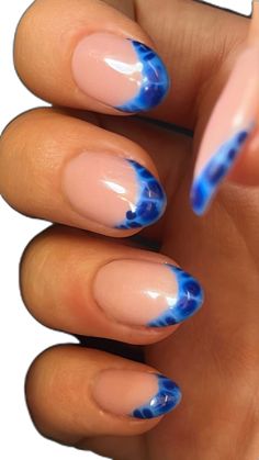 a woman's hand with blue and pink manies on it, holding up her nails