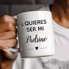 a man holding a white coffee mug with the words queres ser mi padino on it