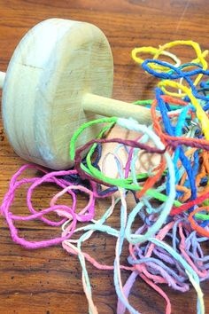 a pile of colorful thread next to a wooden toy