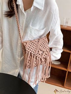 a woman wearing a white shirt is holding a pink bag with fringes on it