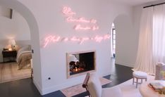 a living room filled with furniture and a fire place next to a white wall covered in neon lights