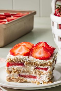 there is a piece of cake with strawberries on the plate next to it and a container of strawberries in the background