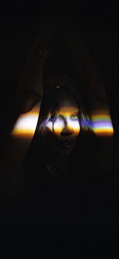 a woman's face is reflected in the dark with light coming through her eyes