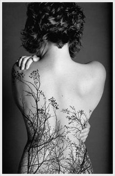 the back of a woman's body with trees on it