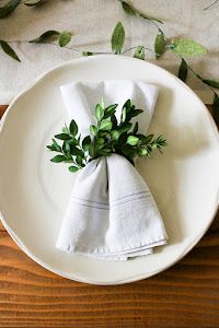 a white plate topped with a napkin covered in green leaves