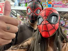 a man and woman wearing masks giving the thumbs up in front of a store display