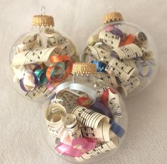 several ornaments made out of sheet music are sitting in a glass ornament on a table