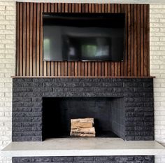 a fireplace with a flat screen tv mounted above it and wood paneling on the wall