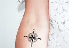 a woman's arm with a compass tattoo on it