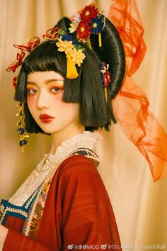 a woman with black hair wearing a red dress and flower headdress is standing in front of a curtain