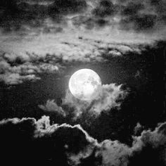 the full moon is seen through clouds in black and white