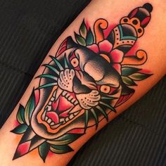 a tiger tattoo on the arm with flowers and leaves around it's neck is shown