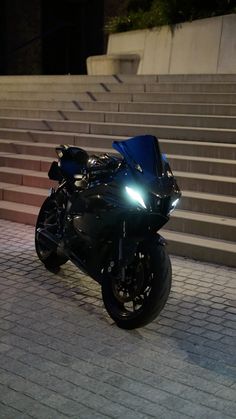 a black motorcycle parked on top of a brick road next to some steps at night