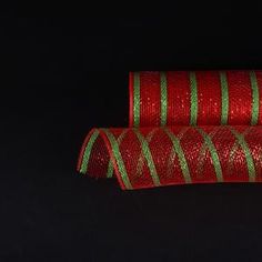 two rolls of red and green christmas ribbon on black background with space for text or image