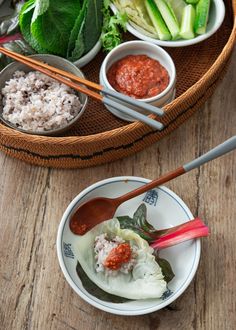 two bowls filled with food and chopsticks on top of a wooden table next to another bowl