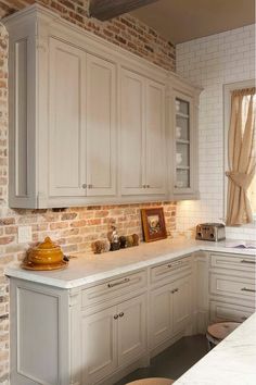 a kitchen with brick walls and white cabinets