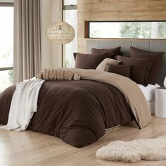 a bed with brown comforter and pillows in a room next to a window,