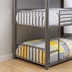 a metal bunk bed sitting next to a wall with a yellow and gray blanket on it