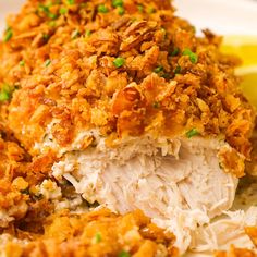 a white plate topped with chicken covered in gravy next to a lemon wedge