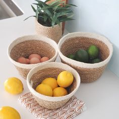 three baskets filled with lemons, limes and eggs on a counter top next to a sink