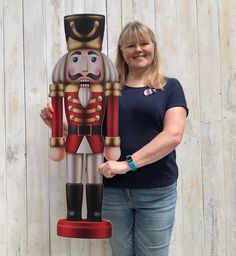 a woman standing next to a large wooden nutcracker holding the nutcracker