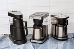 three coffee makers sitting on top of a counter