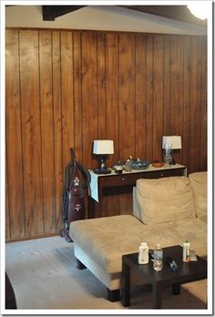 a living room with wood paneling and a couch in front of a coffee table