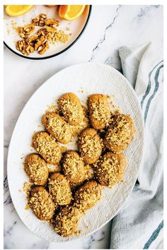 a white plate topped with cookies and oranges next to a bowl of granola