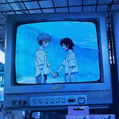 an old tv with anime characters on it's screen and people standing in the background