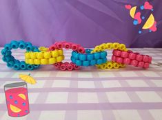 colorful bracelets made out of plastic beads on a table with an umbrella and drink