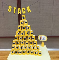 a stack of yellow cups sitting on top of a wooden table next to a sign