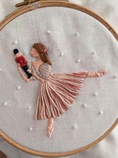 a woman is holding a bottle in her hand while she's working on an embroidery project