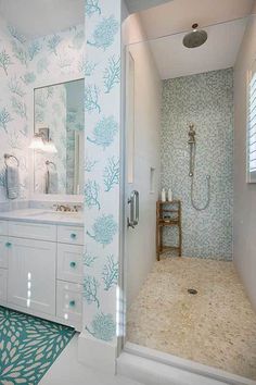 a bathroom with blue and white wallpaper on the walls, along with a walk in shower