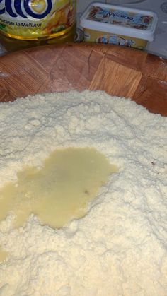 a wooden cutting board topped with flour next to a can of butter and an orange juice